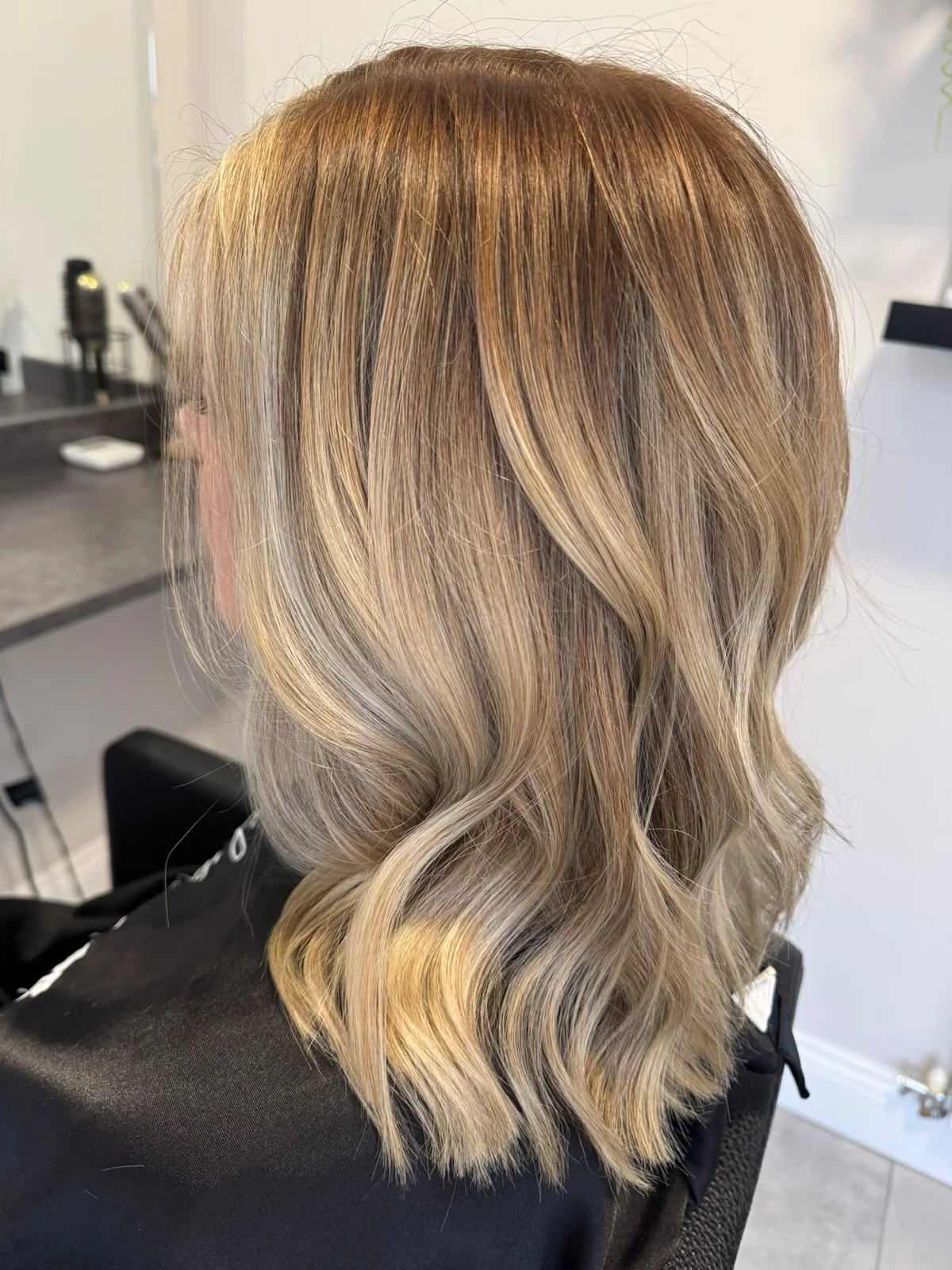 Soft dimensional blonde colour with loose waves, created by Lois